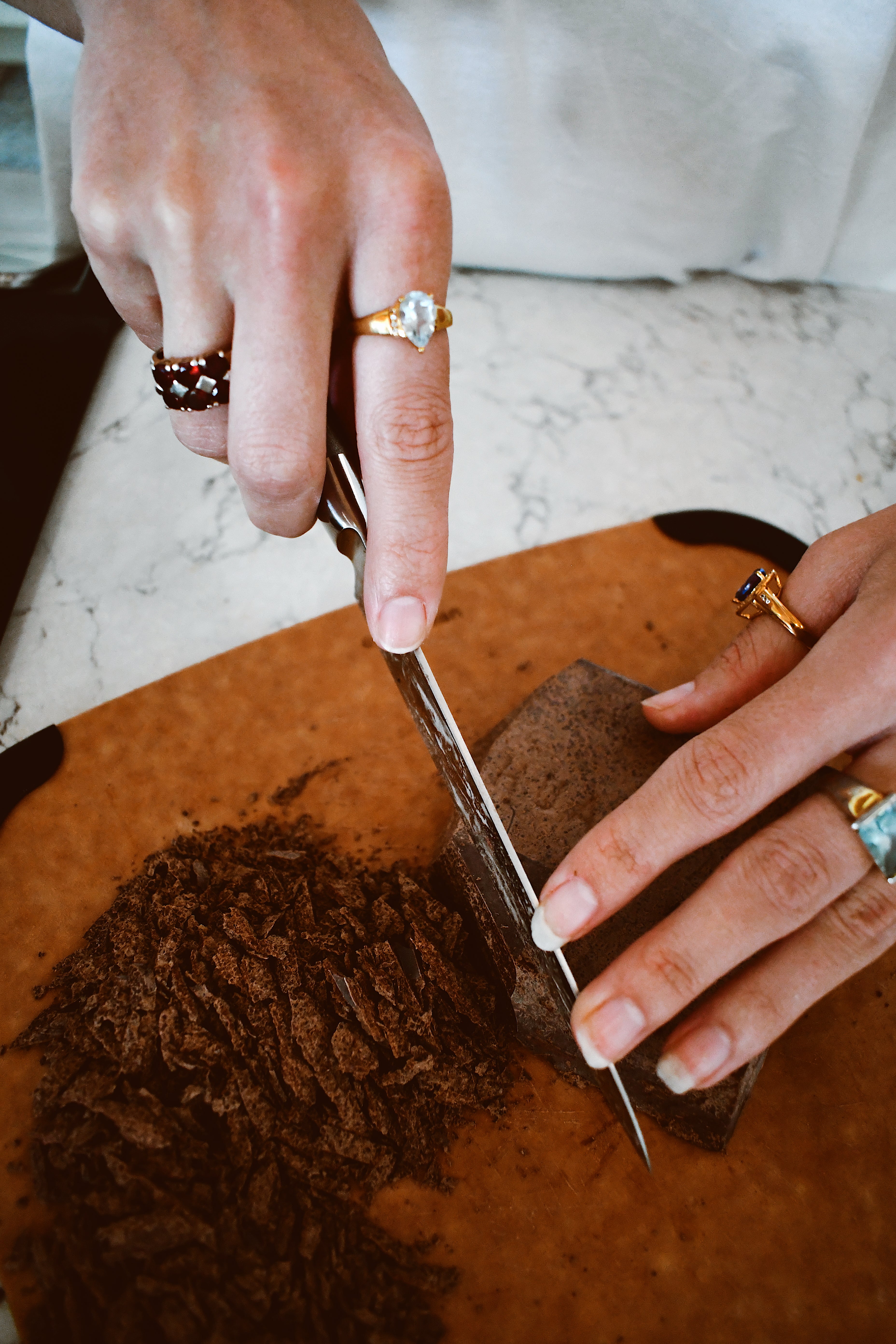 Person cutting chocolate on a wooden board with a knife.